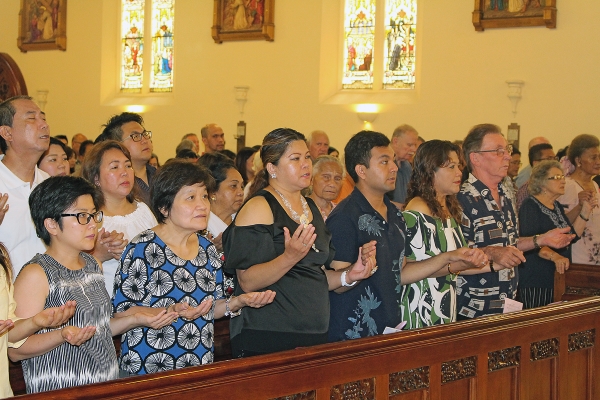 People pray the “Our Father” at Mass at St Patrick’s Cathedral in Auckland on December 17.