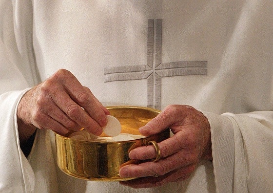 A priest prepares to distribute Communion during Mass in Washington. (CNS photo/Bob Roller)