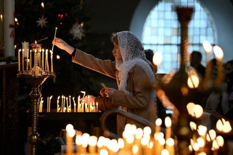 A woman lights a candle during a Christmas liturgy of the Ukrainian Orthodox Church community in Berlin, Germany on January 7, 2023. (OSV News photo / Annegret Hilse, Reuters)